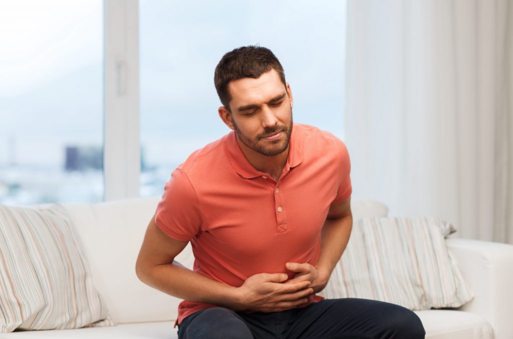 people, healthcare and problem concept - unhappy man suffering from stomach ache at home